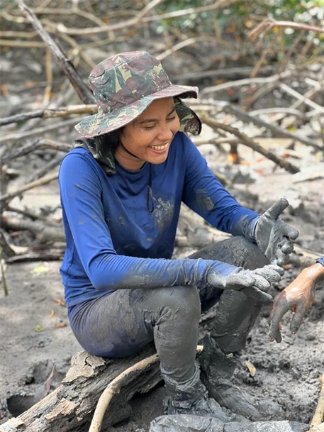 Baumpflanzerin mit Hut macht sitzend Pause am Strand